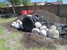 a pile of dirt and rocks in the middle of a yard with a black tarp over it