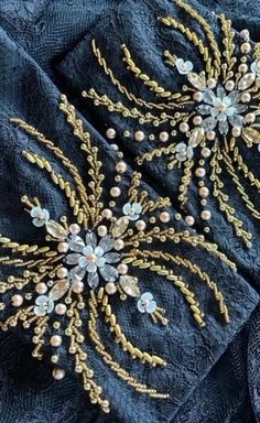 two brooches that are on top of some blue cloth with pearls and beads