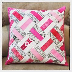 a pink and white pillow sitting on top of a couch