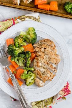 chicken, broccoli and carrots on a white plate with a silver fork