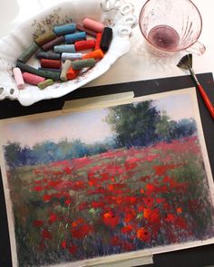 a painting and some crayons are sitting on a table next to a bowl of crayons