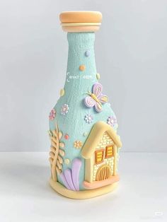 a ceramic bottle with a house and flowers on it