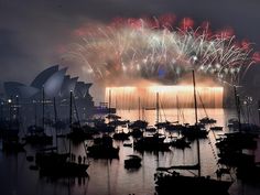 fireworks are lit up over boats in the water near sydney opera on new year's eve