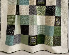 a green and white quilt hanging on the wall