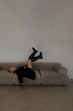 a woman laying on top of a couch with her legs spread out in the air