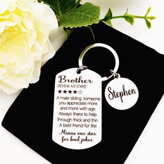 a keychain with the words brother written on it next to a white flower