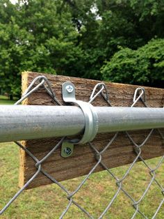 a close up of a chain link fence with a wooden board attached to the post