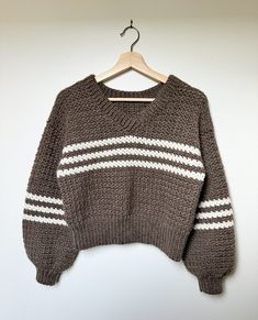 a brown sweater with white stripes hanging on a hanger