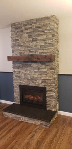 an empty room with a stone fireplace and hardwood floors