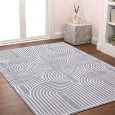 a large rug in the middle of a living room with pink walls and wooden floors