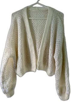 a white knitted sweater hanging on a clothes hanger with the top half open