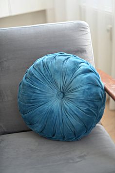 a blue round pillow sitting on top of a gray couch next to a wooden table