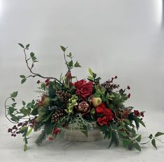 a vase filled with red flowers and greenery