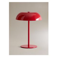 a red table lamp sitting on top of a white surface