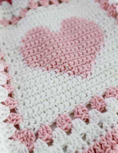 a pink and white crocheted blanket with hearts on it