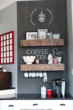 some shelves with coffee cups and other items on them in a room that has gray walls