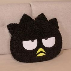 a black angry bird purse sitting on top of a couch next to a white pillow