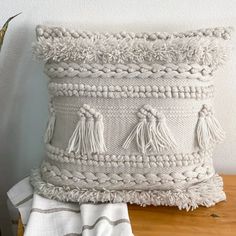 a white pillow sitting on top of a wooden table next to a potted plant