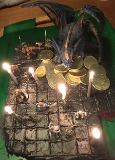 a cake with candles and coins on top of it that is shaped like a dragon