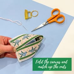 a pair of scissors is being used to sew the zippers on a pouch