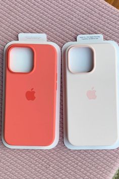 two iphone cases sitting next to each other on top of a pink blanket with an apple logo