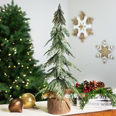 a small christmas tree sitting on top of a table next to a box filled with presents