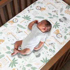 a baby laying on top of a wooden crib