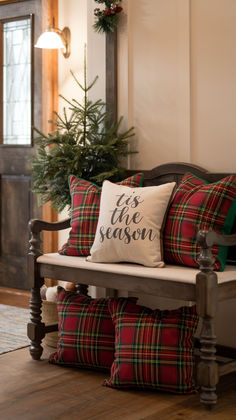 a wooden bench with pillows on it in front of a christmas tree and fireplace mantel