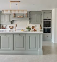 a large kitchen with gray cabinets and white counter tops, along with an island in the middle