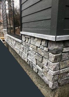 the side of a house with black siding and stonework on it's sides