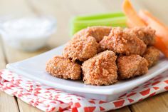 a white plate topped with meatballs next to carrots and celery sticks