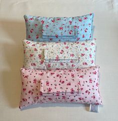 four pillows stacked on top of each other in different colors and patterns, one with a zippered closure