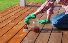 a person in green gloves painting a wooden deck