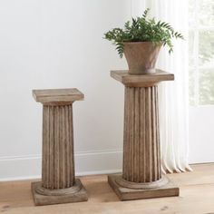 two vases with plants in them sitting next to each other on a wooden floor