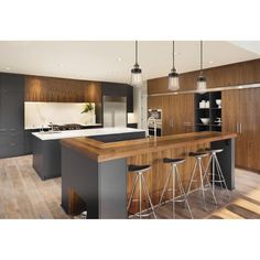 a kitchen with an island and bar stools in the center, surrounded by wooden flooring