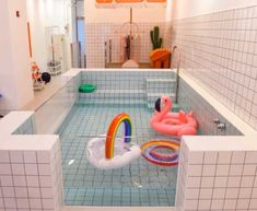 an inflatable flamingo floating on top of a pool surrounded by white tiled walls