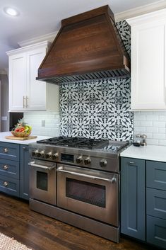 a stove top oven sitting inside of a kitchen next to white cupboards and drawers