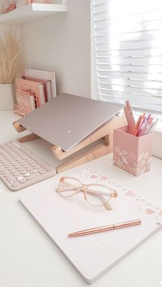 a desk with a laptop, keyboard and glasses on it