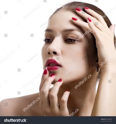 a woman with red nail polish holding her hands to her face and looking at the camera