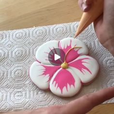 someone is decorating a cookie with pink and white flowers