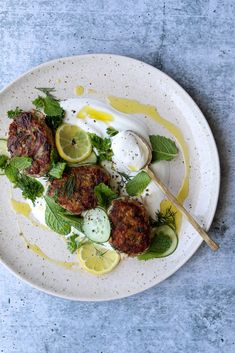 a white plate topped with meat patties covered in yogurt and herb salad