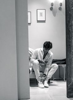 a man sitting on top of a white floor next to a wall with pictures on it