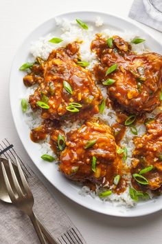 a white plate topped with meat covered in sauce and rice