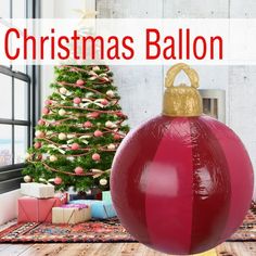 a large red ball sitting in front of a christmas tree