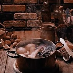 a pot filled with boiling mushrooms on top of a wooden table next to pots and pans