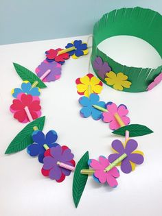 paper flowers and leaves are arranged on a white surface with a green band around them