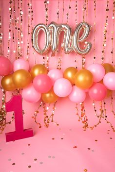 a pink and gold 1st birthday party with balloons, confetti and streamers