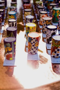 many colorful cups are lined up on a table