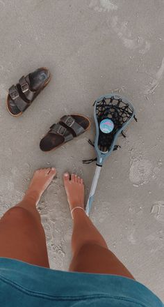 a person standing next to some shoes on the beach