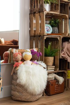 a basket with stuffed animals in it sitting on the floor next to a wall filled with wooden crates